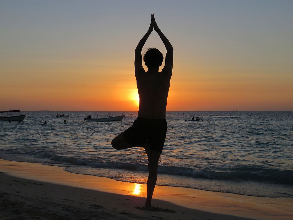 Free silhouette of a woman doing yoga on a beach image, public domain CC0 photo.