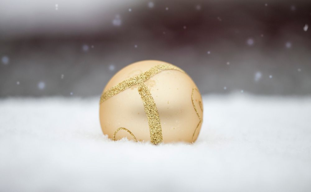 Gold Christmas ball in snow. Free public domain CC0 photo.