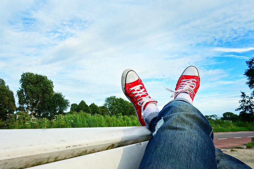 Free person laying crossed leg with red sneakers image, public domain shoes CC0 photo.