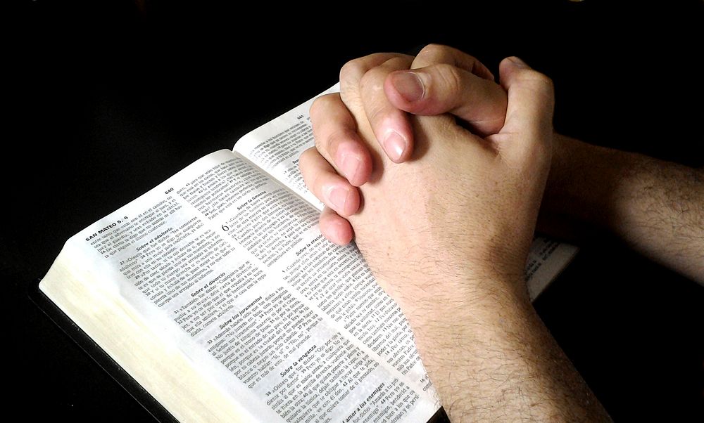 Free praying hands on open book photo, public domain CC0 image.