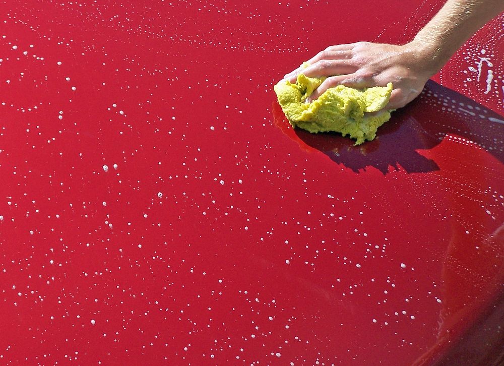 Washing red car with sponge close up hoto, free public domain CC0 image.