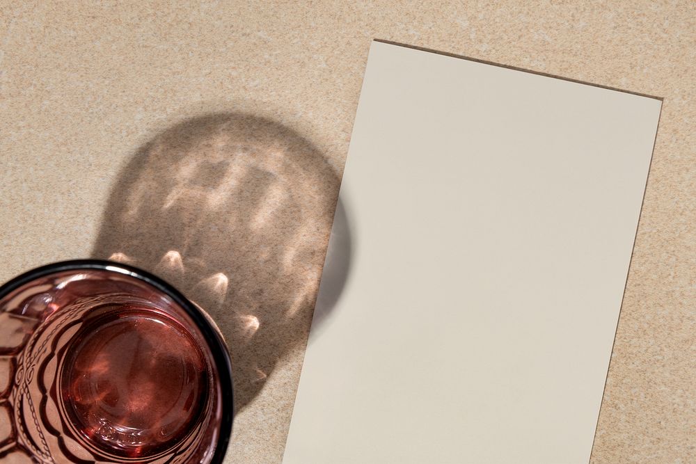 Blank beige paper flat lay with glass shadow