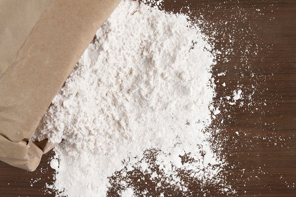 Flour in bag, wooden background