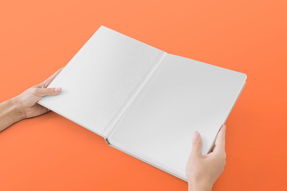 Hands holding open book on orange background