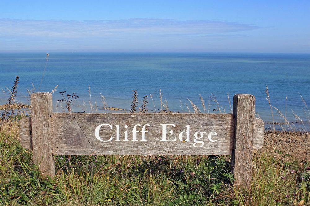 Cliff edge sign infront of ocean photo, free public domain CC0 image.
