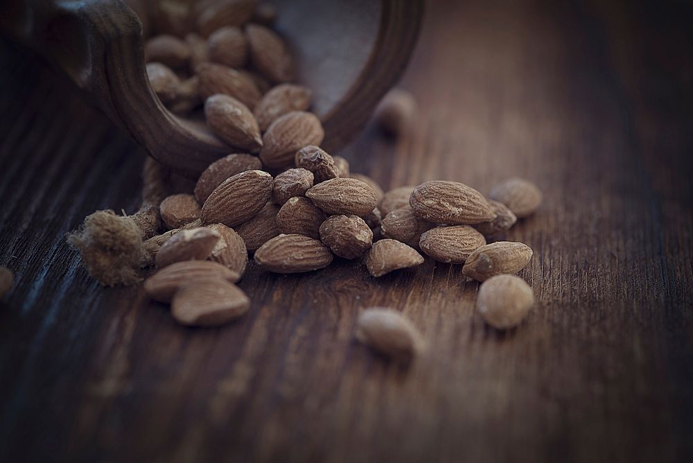 Free bunch of almonds on wooden table image, public domain nuts CC0 photo.