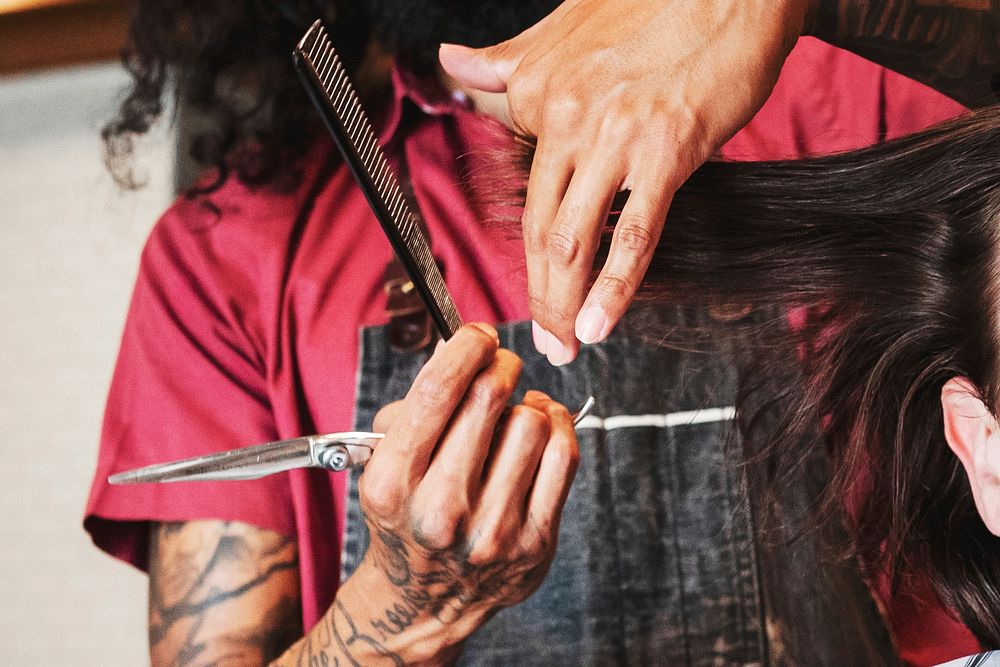 Hair stylist trimming hair of the customer at a barbershop, small business