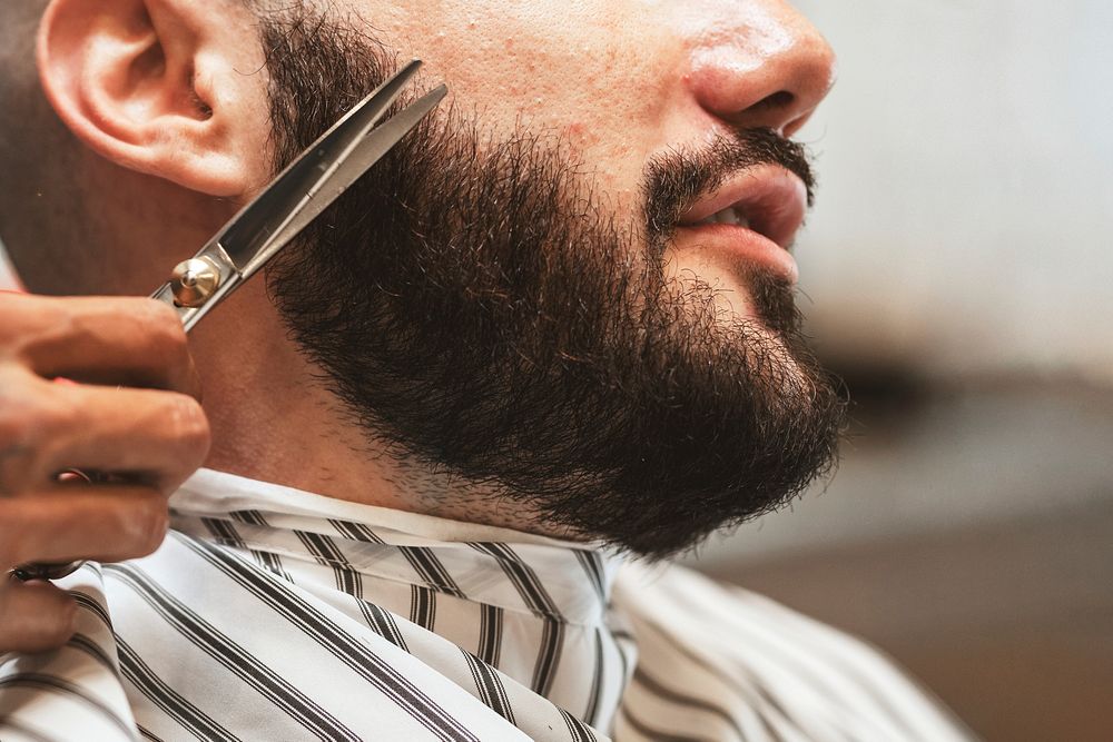 Customer getting a beard trim in a barber shop, small business