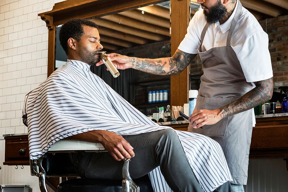 Barber trimming a customer's beard at a barber shop, small business