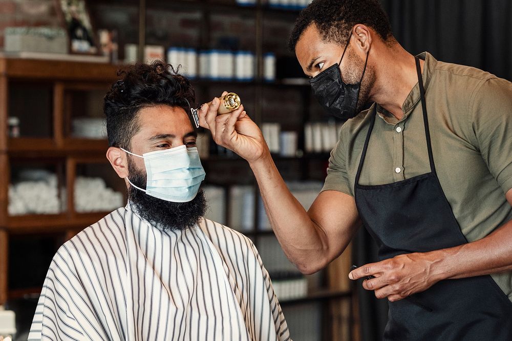 Barber trimming a customer's hair at a barber shop, small business