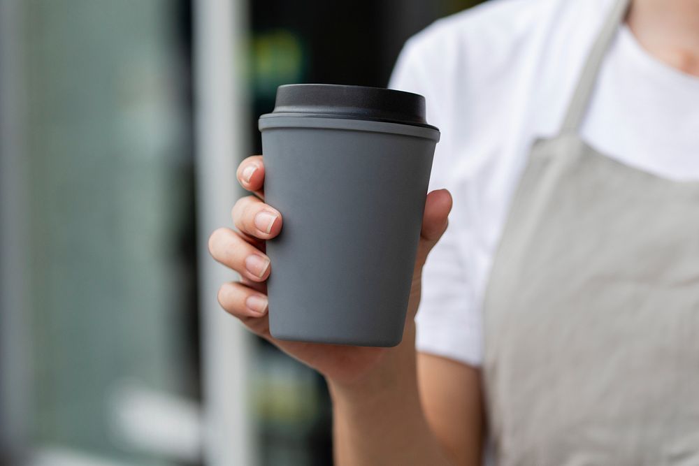 Barista holding gray takeaway coffee cup