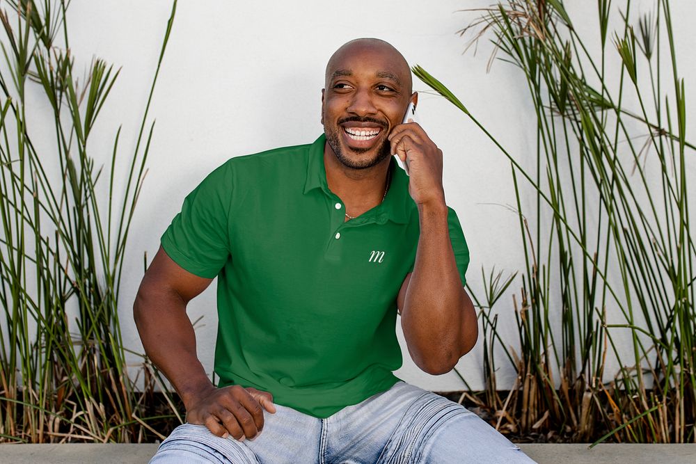 Happy African American man on a phone call, wearing green polo shirt