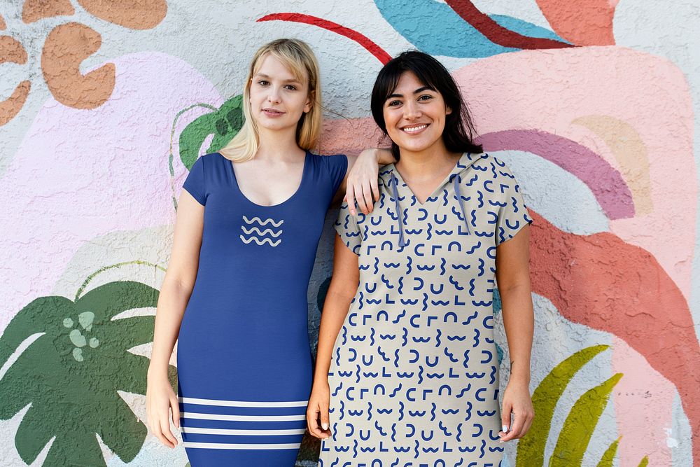 Two women wearing dresses, posing by a summer graffiti art