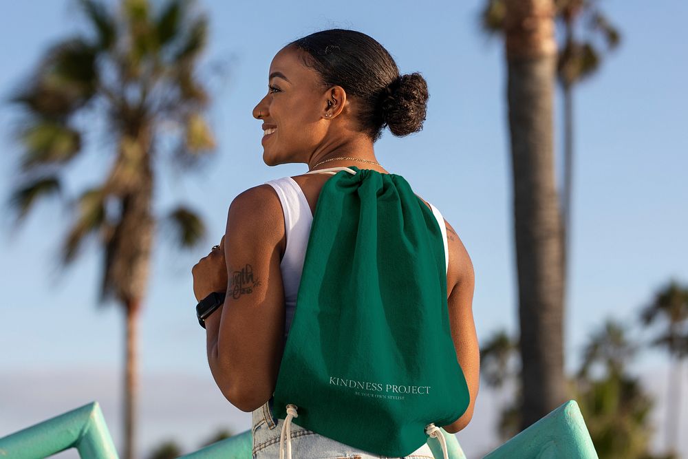 Woman carrying drawstring bag at the beach, green accessory