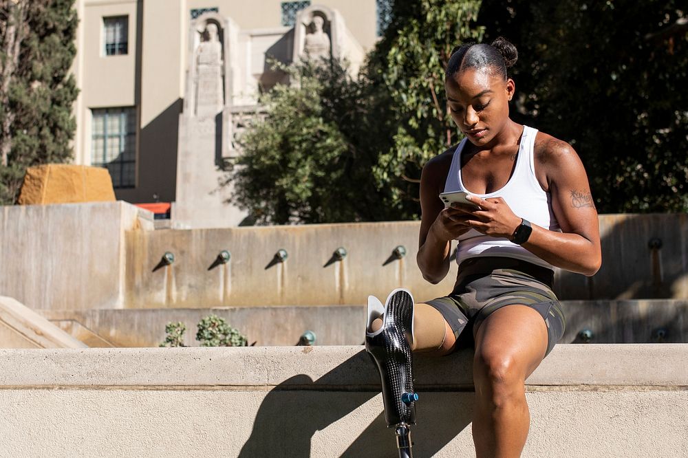 Athlete with prosthetic leg resting and texting her friend