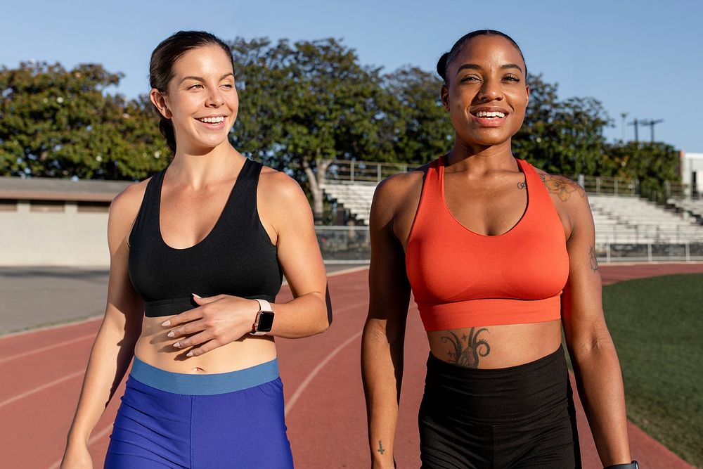 Two athletes laughing and talking to one another while on a running track 