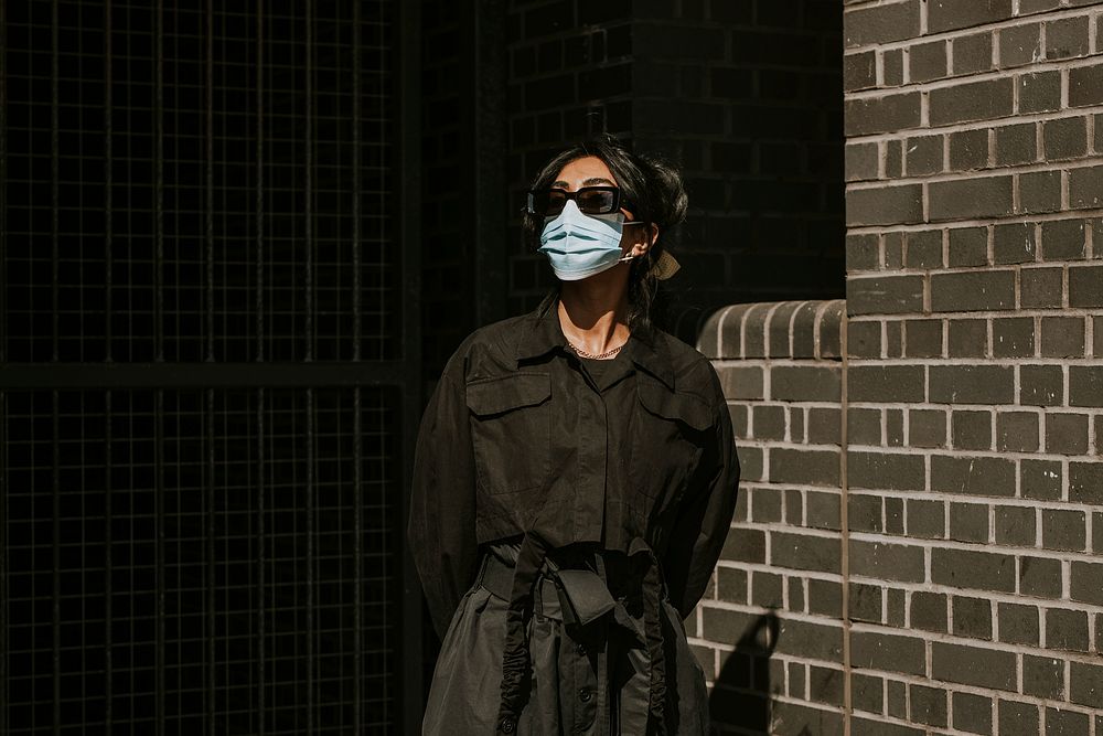 Indian woman wearing mask posing by the brick wall 
