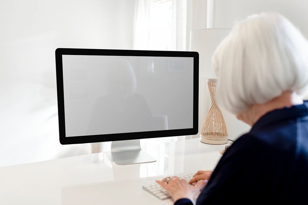 Blank computer screen, senior woman typing on keyboard