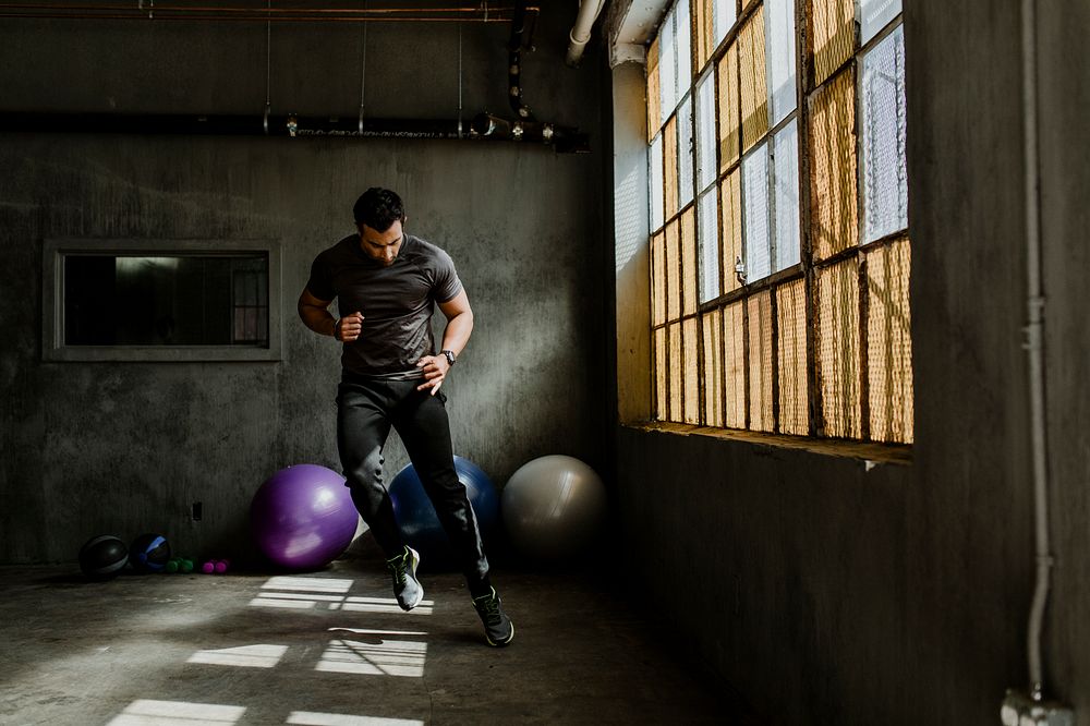 Sportive man doing a side to side jump in a gym