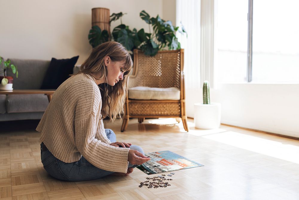 Woman assembling a jigsaw puzzle of Nyhavn, Copenhagen during coronavirus quarantine.