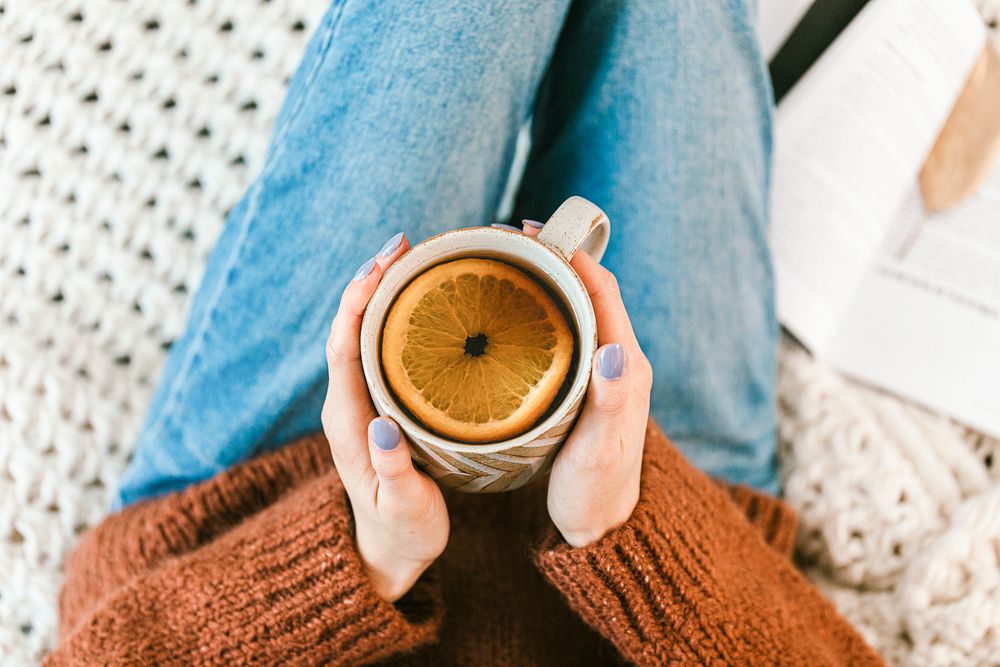 Woman drinking a cup of warm herbal orange tea