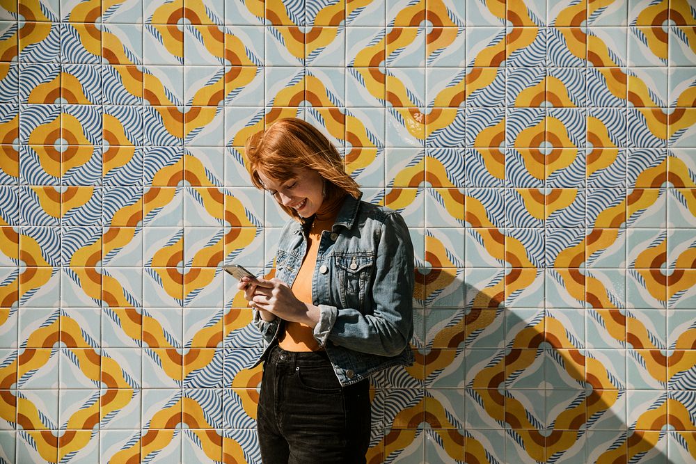 Woman using her phone at a modern patterned wall