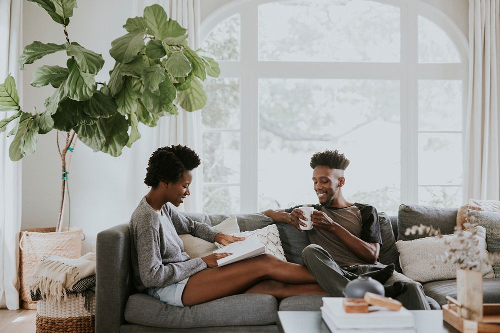 Black couple reading a book together on the couch