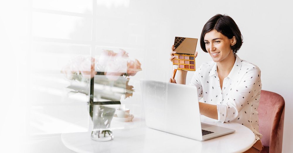 Happy women displaying an eye shadow palette with a laptop