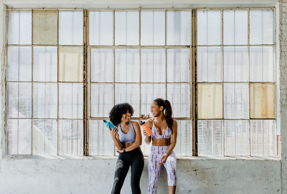 Sportive women talking in a gym while drinking water