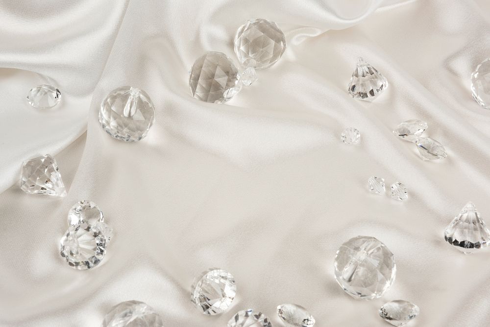 Decorative clear diamonds on white fabric textured background