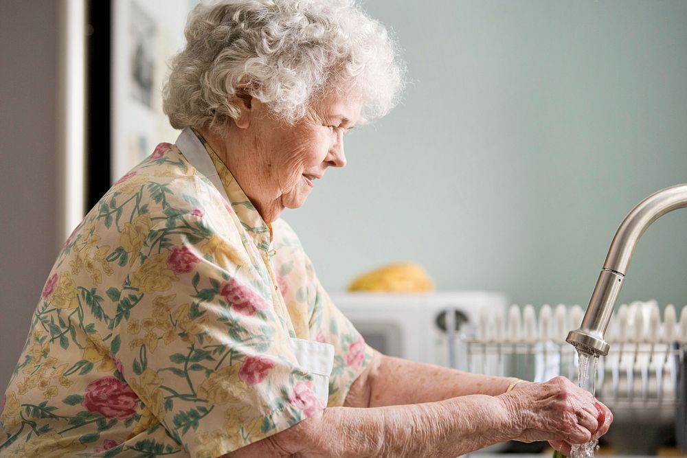 Grandmother properly cleaning fresh, uncooked produce under a running tap. Original image sourced from US Government…