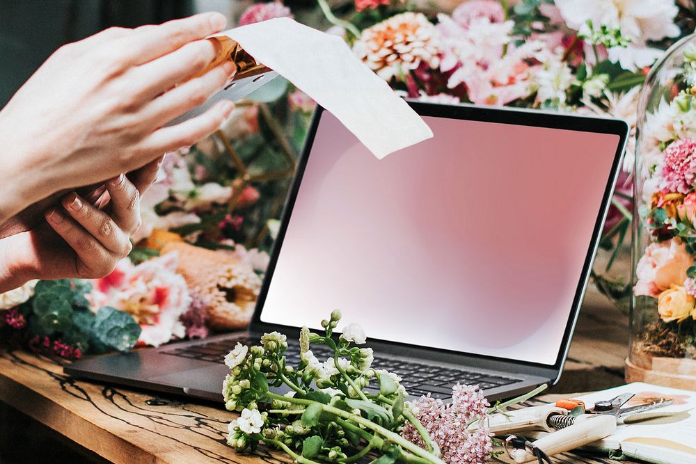 Florist creating designs on her laptop in a flower shop