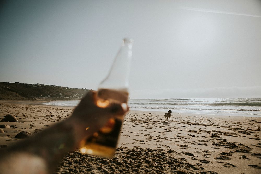 Holding a beer bottle on the beach