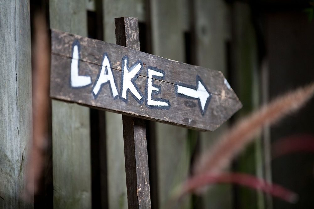A close up on a hand-painted wooden sign, which reads "Lake" with an arrow pointing right. You know where to find me.