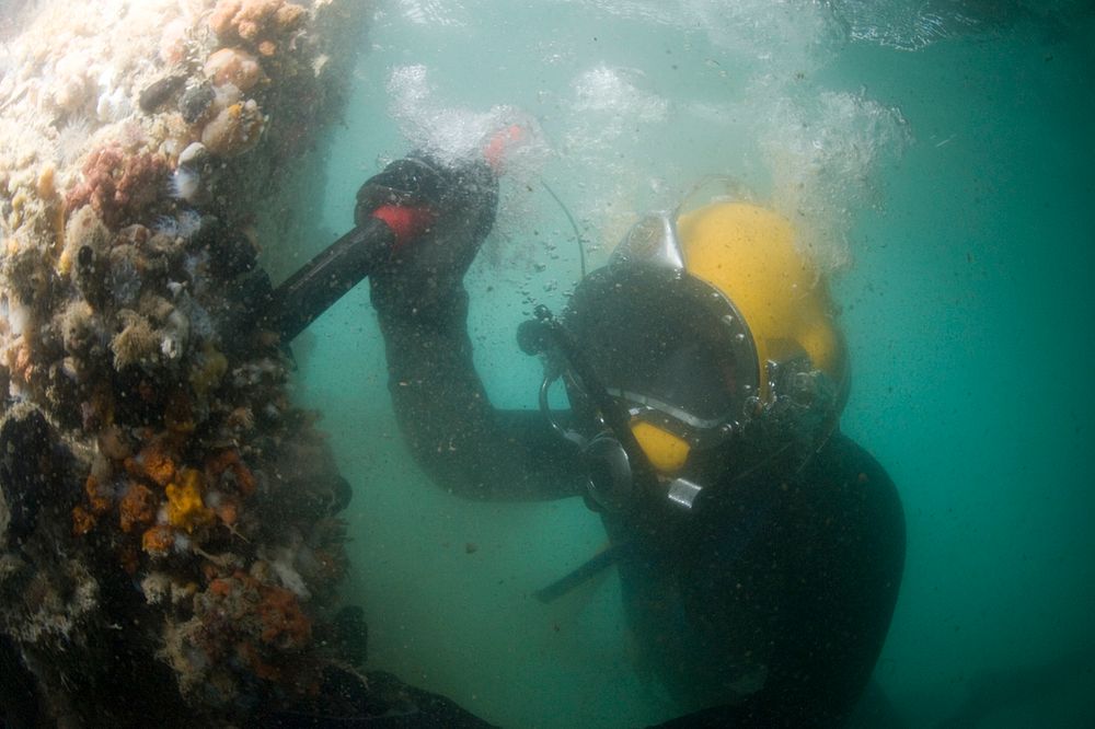 U.S. Navy Diver 1st Class John Neal, assigned to Mobile Diving and Salvage Unit 2, inspects a damaged pier Jan. 25, 2010, in…