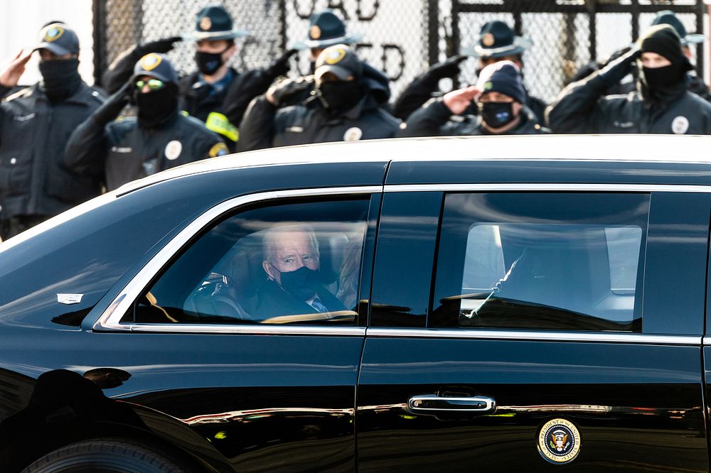 President Joe Biden looks out the window of the Presidential limousine Wednesday, Jan. 20, 2021, as he travels by motorcade…