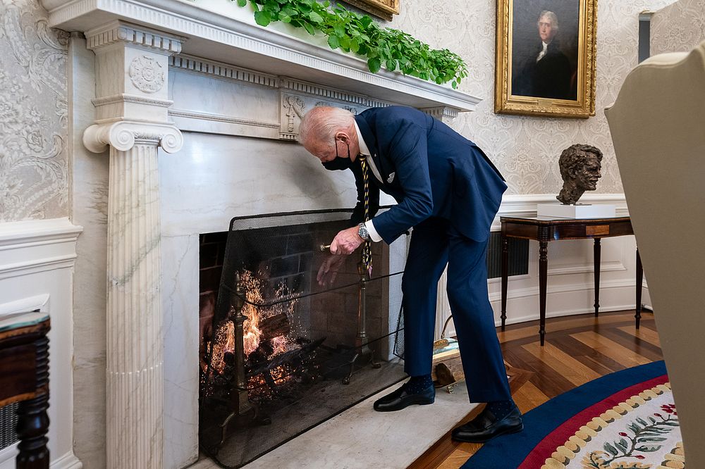 President Joe Biden adds a log to the fire in the Oval Office of the White House Friday, Jan 22, 2021.