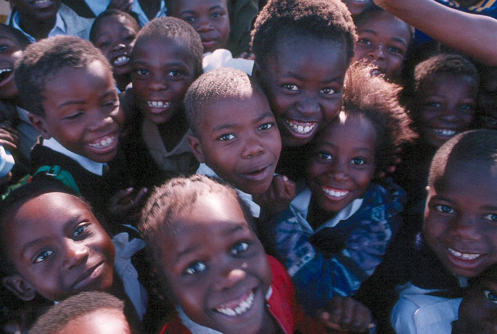 South African children huddled together and smile for a photo taken by a Peace Corps Volunteer. Original public domain image…