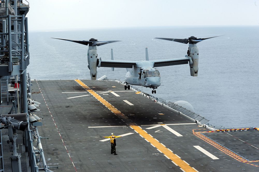 A U.S. Navy landing signalman directs a Marine Corps MV-22 Osprey aircraft assigned to Marine Medium Tiltrotor Squadron…