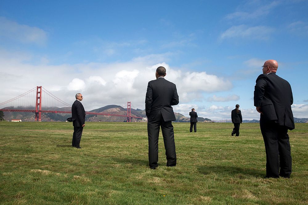 President Barack Obama stands with U.S. Secret Service agents and looks at the Golden Gate Bridge, prior to boarding Marine…