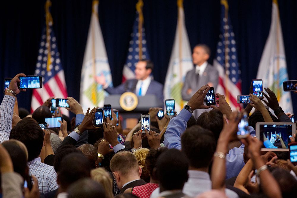 Audience members photograph HUD Secretary Juli&aacute;n Castro introducing President Barack Obama at the Department of…