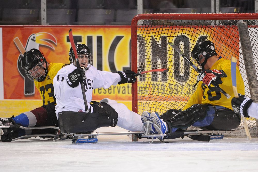 Air Force Senior Airman Nikole Sweeney, center, reacts to scoring a goal during a sled hockey game at the World Arena in…
