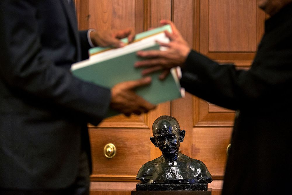 A bust of Mahatma Gandhi is featured as President Barack Obama and President Pranab Mukherjee hold a book together at…