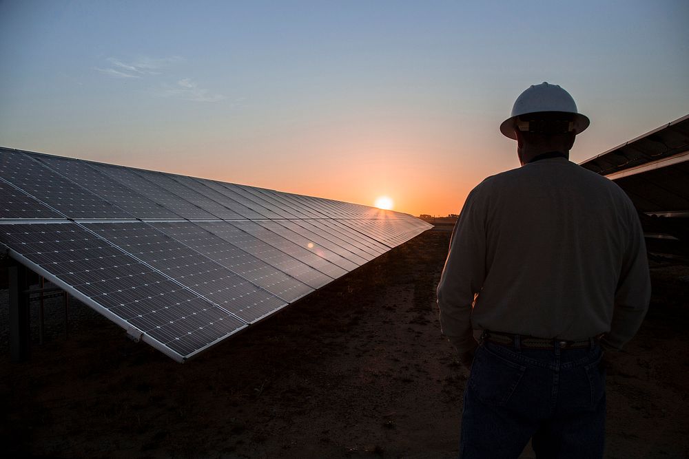 A worker watches the sunrise at a Solar Station, Texas. Original public domain image from Flickr