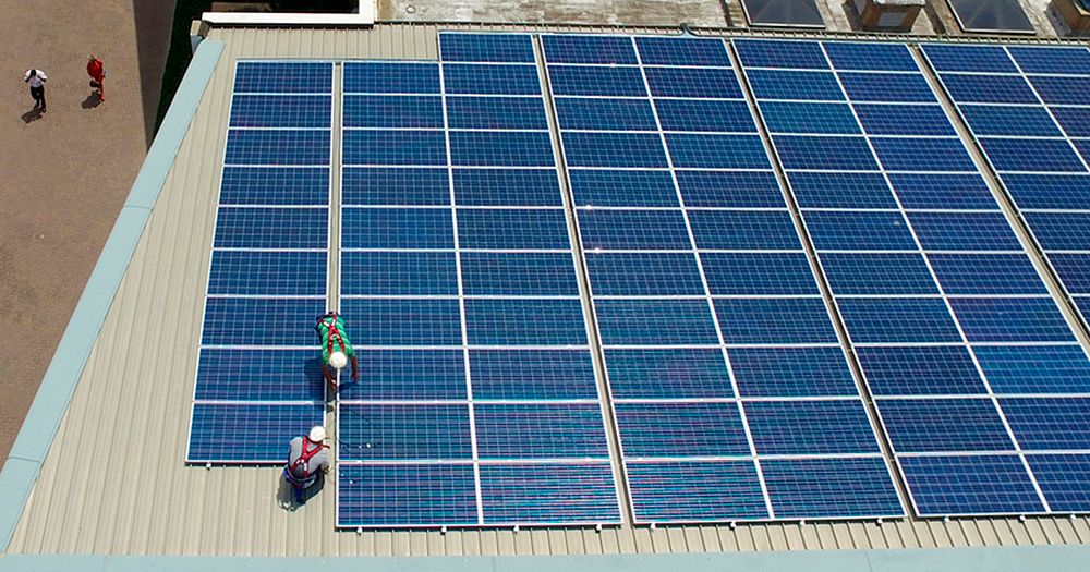 Workers installing photovoltaic solar panels. Original public domain image from Flickr