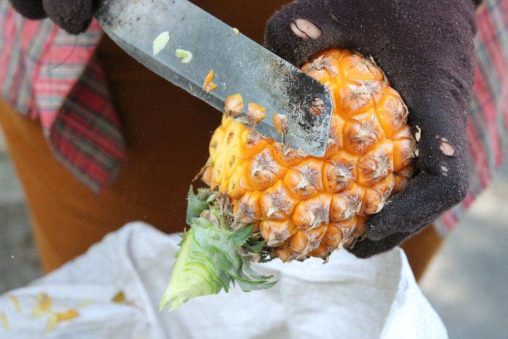 Person cutting up a fresh pineapple. Free public domain CC0 image. 