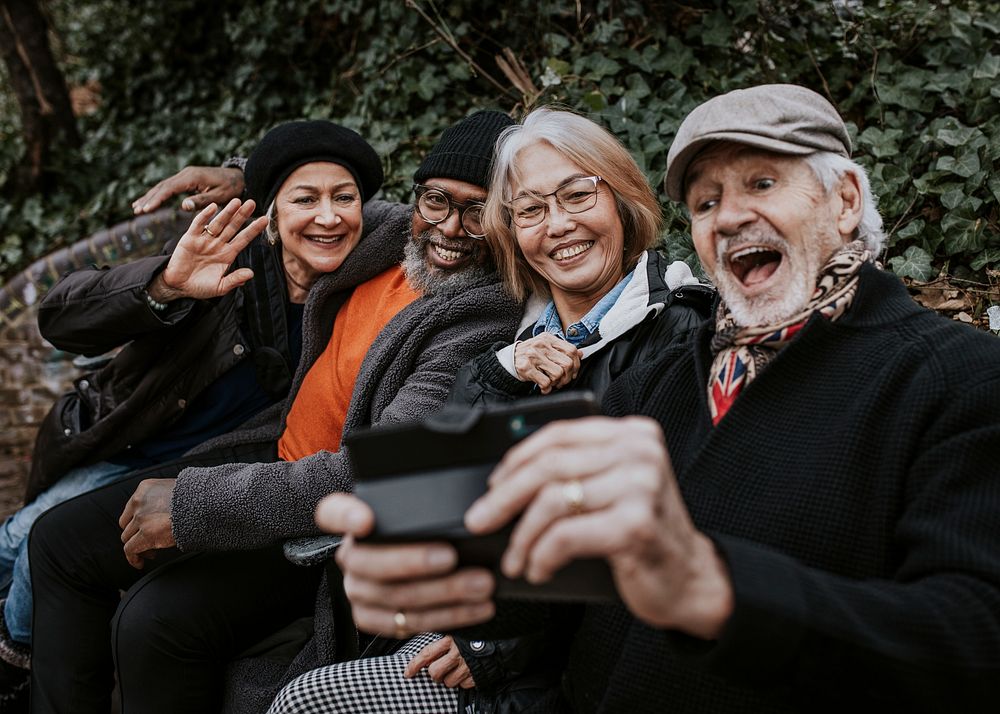 Senior friends taking selfie at a park bench