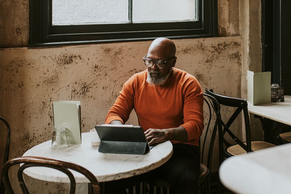 Man working on digital tablet at coffee shop