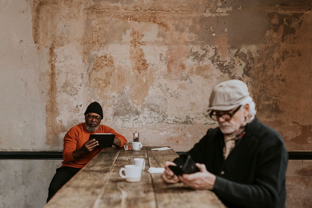 Senior men using social media at cafe 