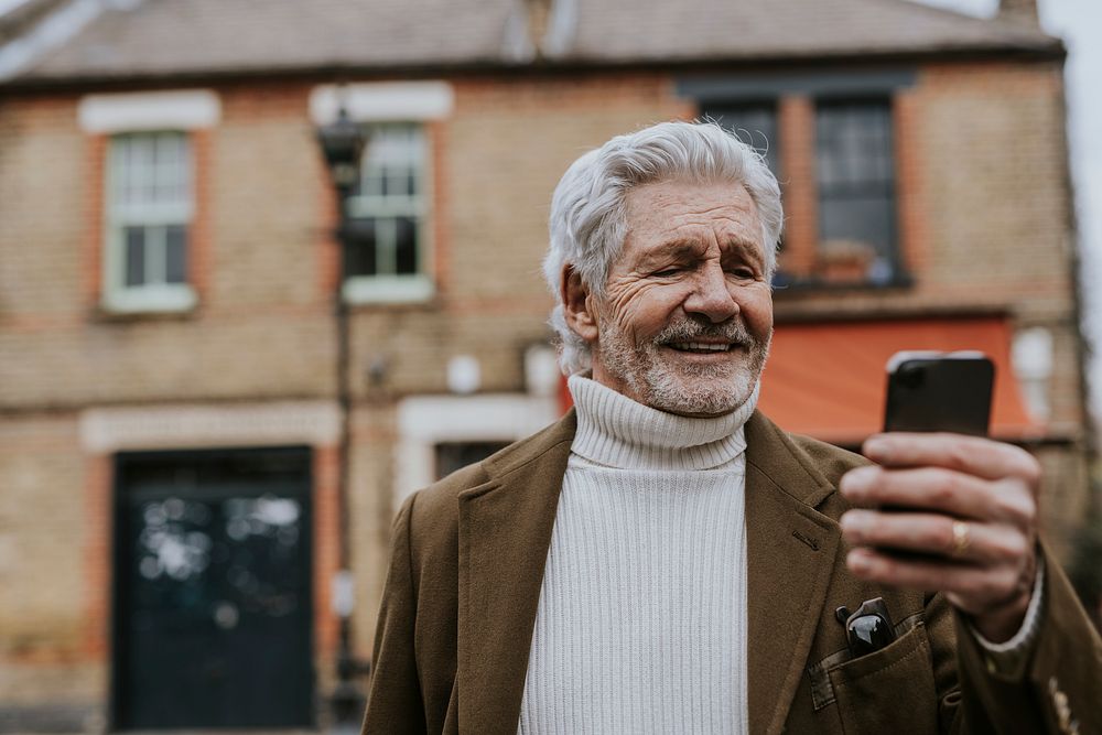 Retired man checking phone outdoors